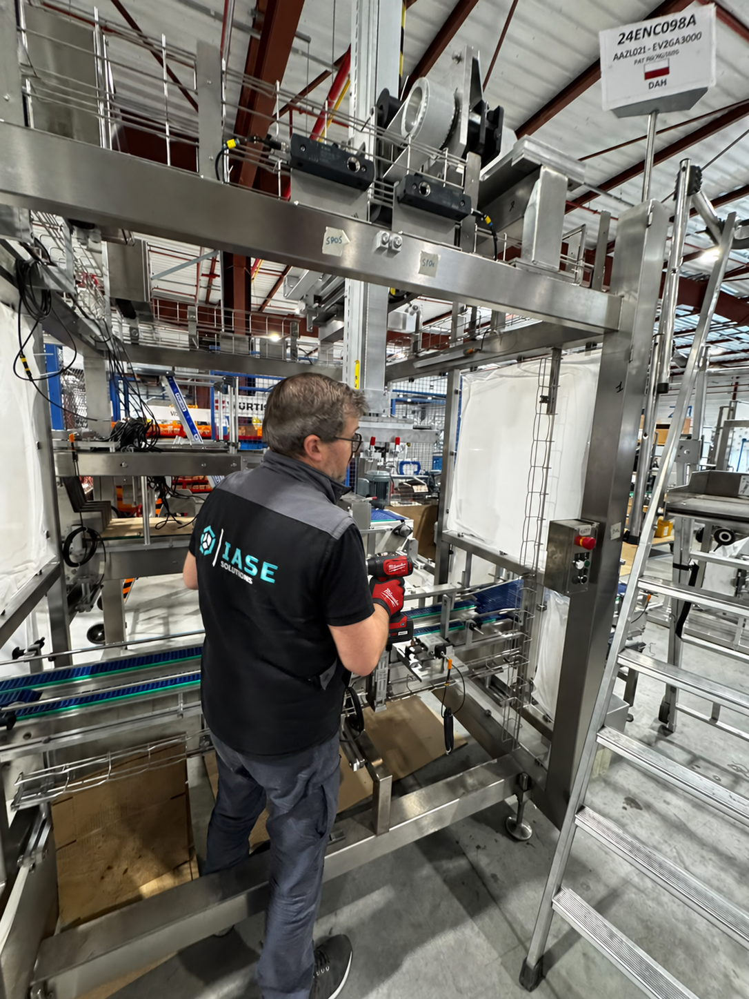 Profissional com uniforme IASE a trabalhar numa estrutura de máquina industrial